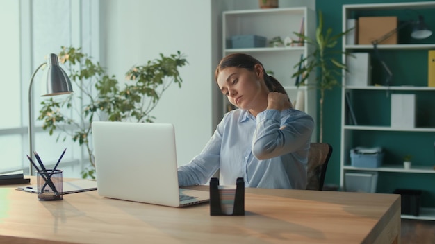 Photo focused woman work at a table with a laptop suddenly feeling pain in neck