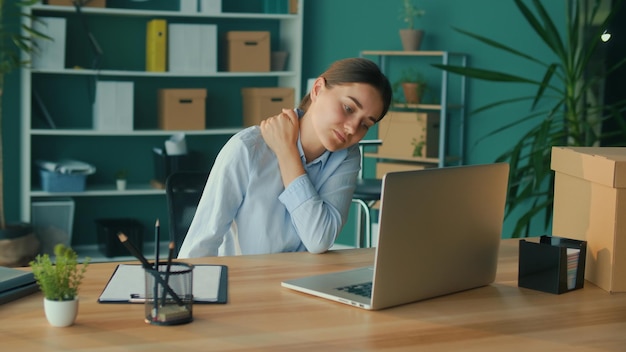 Foto la donna concentrata lavora a un tavolo con un laptop sentendo improvvisamente dolore al collo