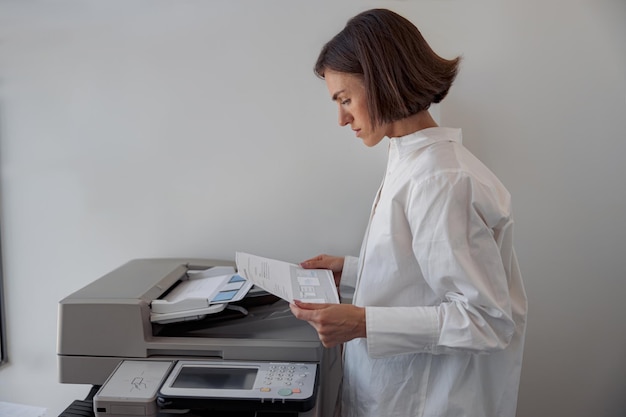 Focused woman worker scanning a document on photocopy machine In modern office