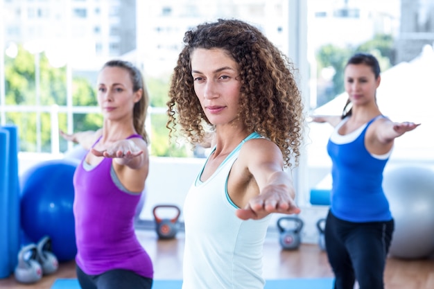 Focused women doing warrior II pose