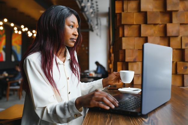 Focused young african american businesswoman or student looking\
at laptop serious black woman working or studying with computer\
doing research or preparing for exam online