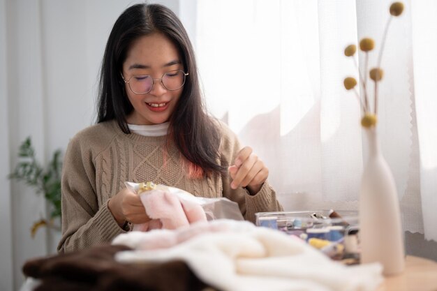 집중적 인 젊은 아시아 여성 이 옷 에 손 으로 는 봉제 프레임 에 패턴 을 고 있다