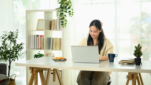 focused young asian woman working in a bright home office