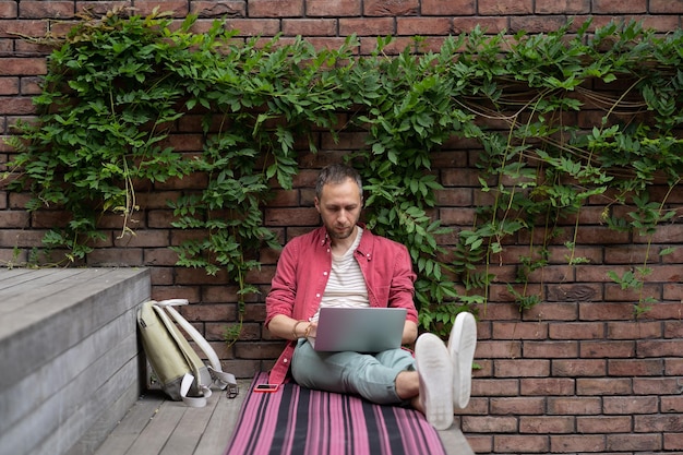 Focused young businessman freelancer engaged in distant work
from street make report on laptop