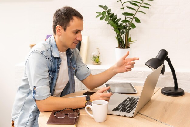 Focused young businessman holding video call with clients on\
laptop. concentrated millennial man in glasses giving online\
educational class lecture, consulting customer.