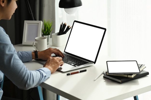 Focalizzato giovane uomo d'affari che lavora con il computer portatile e lavora online in ufficio a casa.