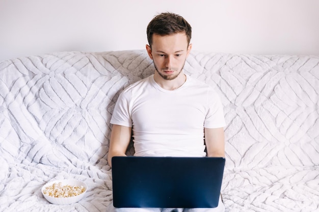 Focused young man using laptop typing on keyboard searching for