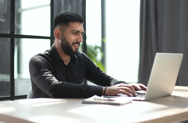 Focused young man wearing using laptop on keyboard writing email or message