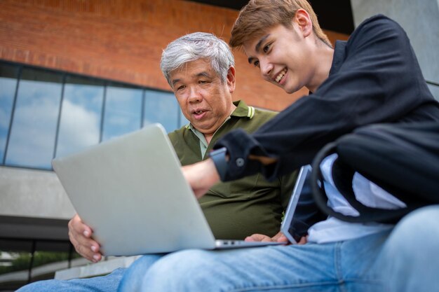 Photo focused young students listening old senior aged teachers for advise capstone project in university happy middle aged teacher working together with students for graduation project