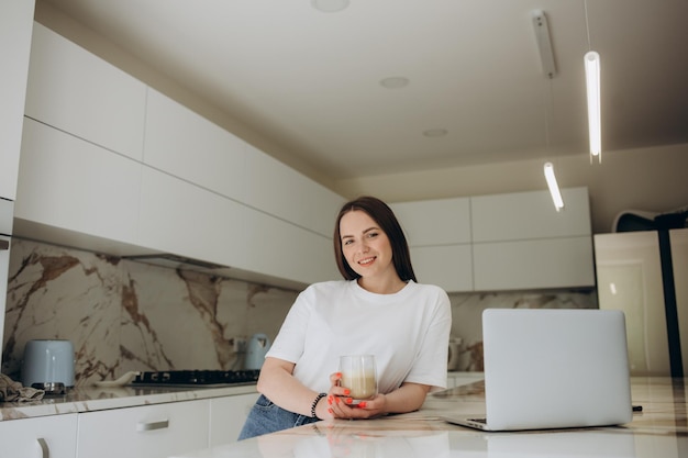 Focused young woman sitting at her kitchen table at home working on her small business with a laptop