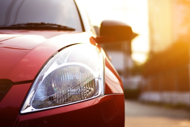 Foto mettendo a fuoco sui fari dell'automobile rossi sulla via con i chiarori di luce solare.