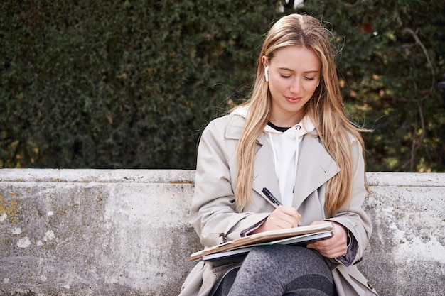 Focussed Caucasian woman multitasking with music and studying