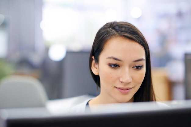 Focussing on her work with a positive spirit Shot of an attractive young woman sitting at her workstation in the office