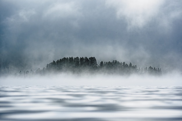 Fog-covered forest on the shore of a mountain lake in the Ulagansky District of the Altai republic, Russia