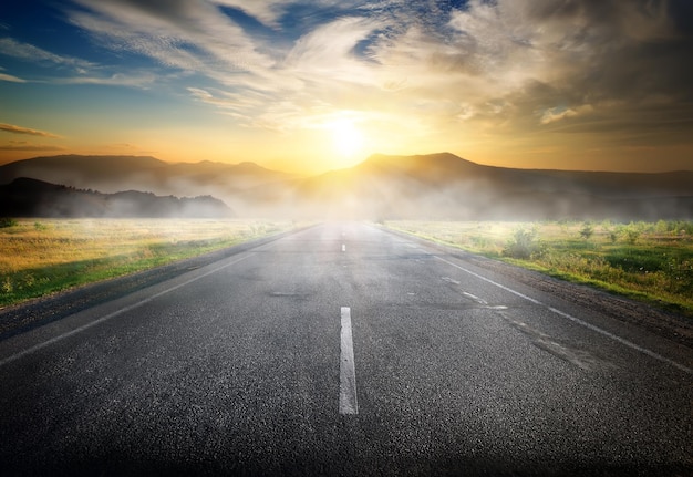 Fog over highway to mountains at sunrise