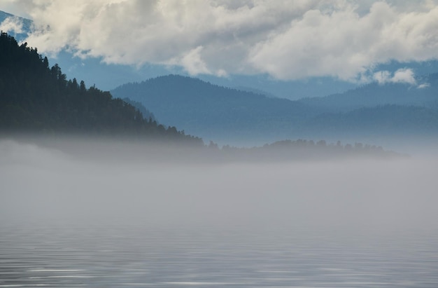 Fog in the mountain valley Morning fog over the lake in the Altai mountains