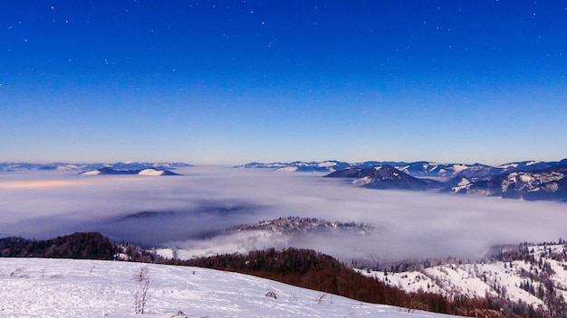 Fog moving over the mountain in winter with a starshaped sky