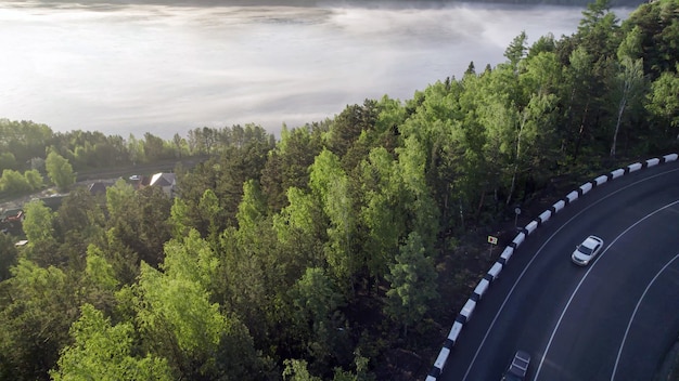 Fog over the river forest and the edge of the asphalt road on the hill beautiful view of the travel landscape