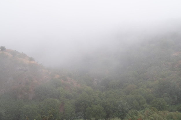 Fog view on the Khndzoresk suspension bridge in the cave city in the mountain rocks Armenia landscape attraction Abandoned ruins in the mist Atmospheric stock photo