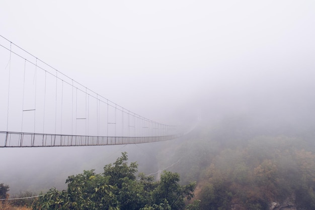 Fog view on the Khndzoresk suspension bridge in the cave city in the mountain rocks Armenia landscape attraction Atmospheric stock photo