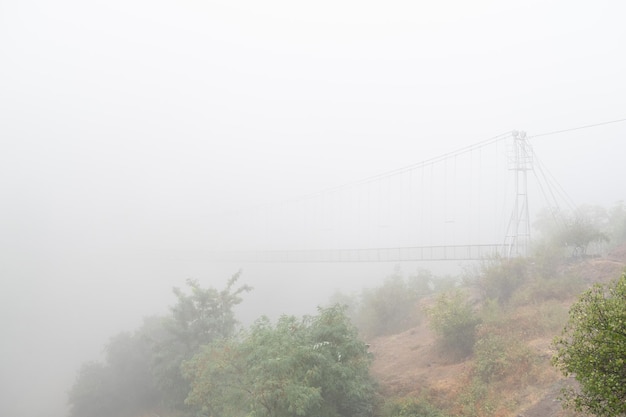 Photo fog view on the khndzoresk suspension bridge in the cave city in the mountain rocks armenia landscape attraction atmospheric stock photo