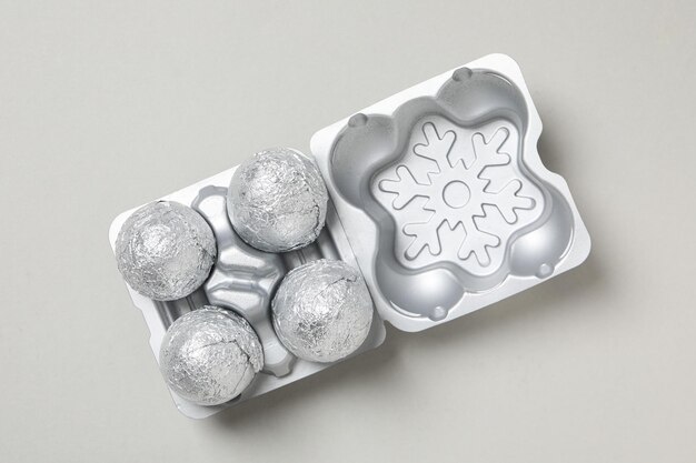 Foil balls in silver case on light gray background top view