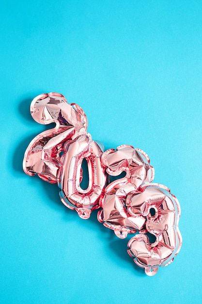 Foil pink balloons numbers 2023 on blue background New year concept