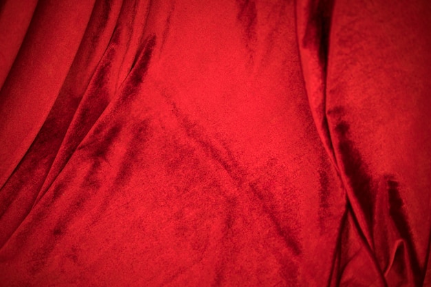 柔らかい波打つ赤いベロアの布のテクスチャの背景を折る。