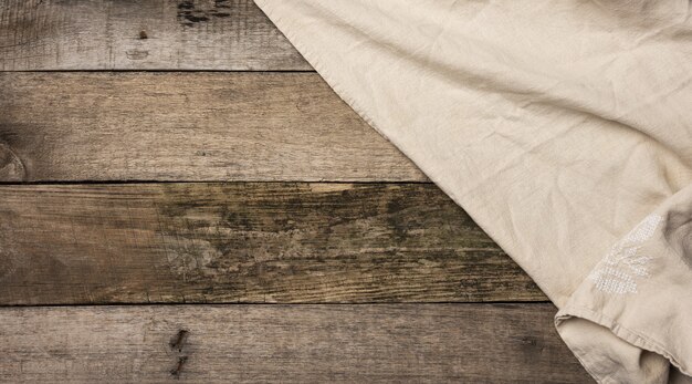 Folded beige linen towel on a table made of old gray wooden boards, top view, copy space