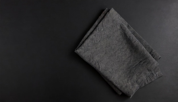 Photo folded black linen linen kitchen towel on a black background top view