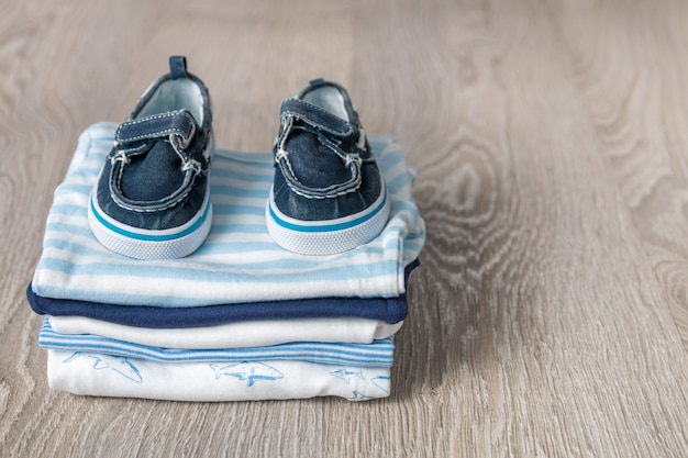 Folded blue and white bodysuit with shoes on it on grey wooden background. 