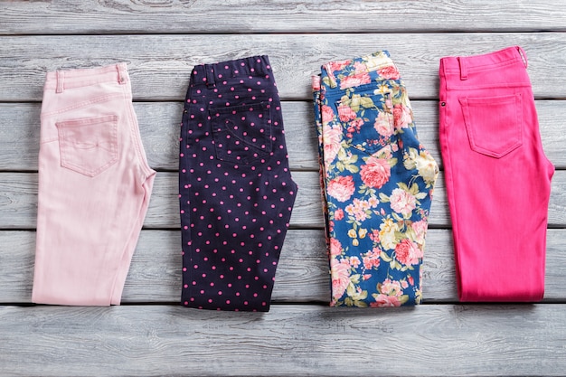 Folded colorful pants. Woman&amp;#39;s casual trousers with print. Merchandise on gray wooden shelf. Discounted goods of high quality.