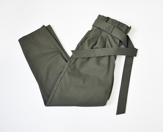 Photo folded khaki green pants with belt flat lay on white