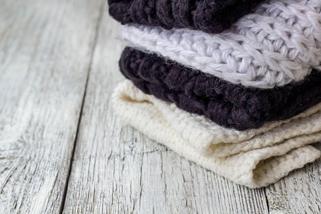 Folded knitted things white and black on a white wooden background