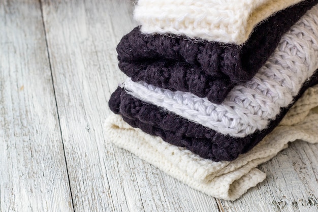 Folded knitted things white and black on a white wooden 