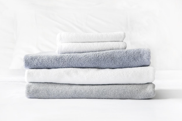 Folded terry towels lie on clean white bed Cleaning in guest room of hotel cleanliness laundry