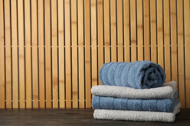 Folded towels on wooden table on bamboo, space for text