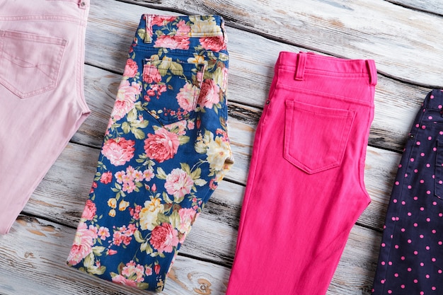folded trousers of different color. trendy pants on wooden background. selection of merchandise on shelf. buy one and get two.