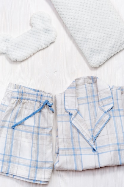 Folded warm white pajamas with blue checks or stripes mask for sleeping pillow