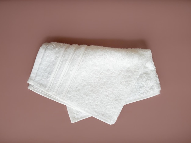 Folded white cotton towel on the beige background