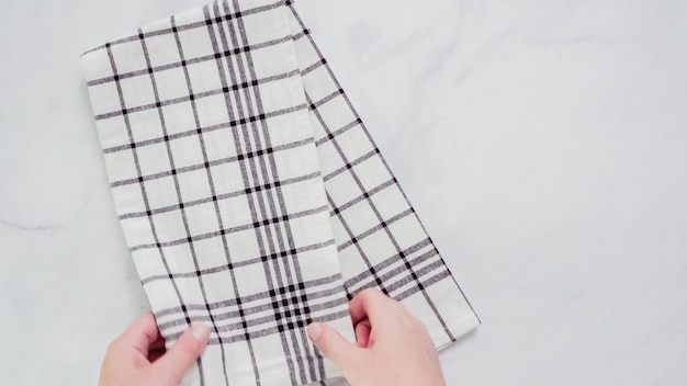 Складывание черно-белых бумажных полотенец с рисунком на мраморной поверхности.