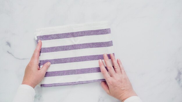 Folding blue and white patterned paper towels on marble surface.