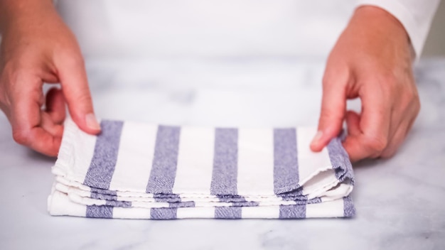 Folding blue and white patterned paper towels on marble surface.