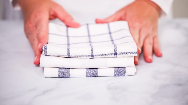Folding blue and white patterned paper towels on marble surface.
