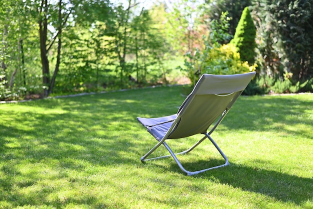 Folding chair surrounded by green leaves in a garden Relaxation in the garden Cottage aesthetics