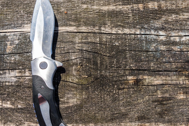 Складной нож на деревенском деревянном фоне