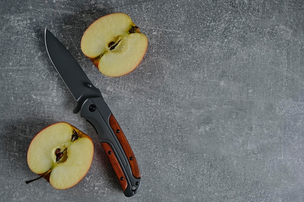 Folding knife for survival and two halves of cut apple