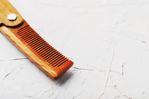 Folding wooden comb on a gray wall.