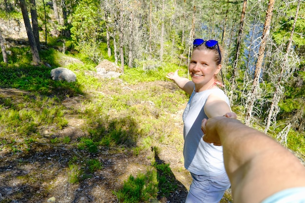 Seguimi una bella donna che si tiene per mano e conduce nella foresta in un giorno d'estate