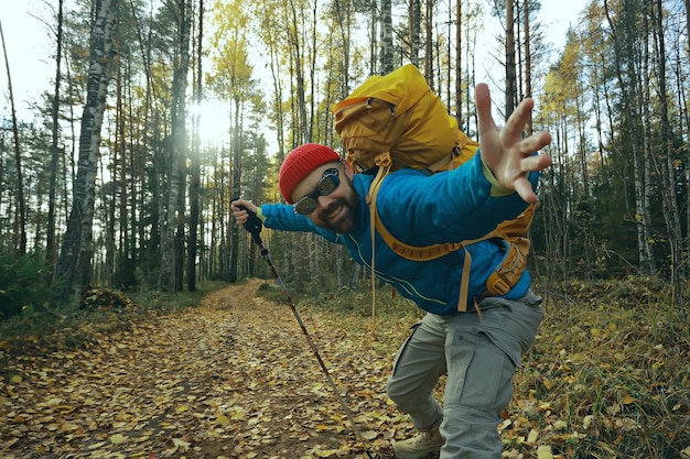 Seguimi in un'escursione, un uomo ti invita a un'escursione nella foresta, paesaggio autunnale nella foresta nella natura